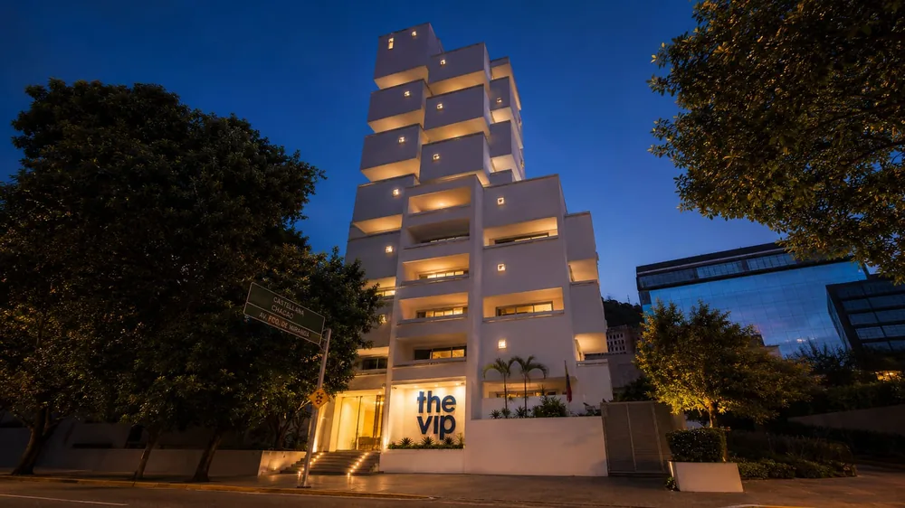 Fachada nocturna iluminada — CUARTA AVENIDA SUITES